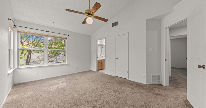 an empty living room with a ceiling fan.